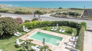 Ein Poolbereich mit Liegestühlen und Blick auf den Ozean.