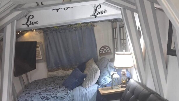 En kompakt bolig med seng, lædersofa, lille bord og lampe.