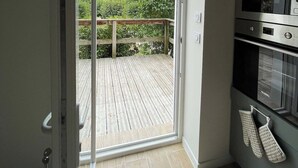 Eine Küche mit Einbauofen und einer Schiebetür zu einer Holzdiele mit Blick auf Grünflächen.