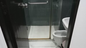A bathroom with a glass shower enclosure, a white toilet, and a small rug on the floor. - Corner Unit @ Acqua  Private Residences - Livingstone Tower (Mandaluyong)