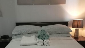 A neatly made bed with rolled towels and a lamp on a bedside table. - Corner Unit @ Acqua  Private Residences - Livingstone Tower (Mandaluyong)
