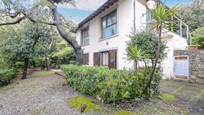 Una casa de dos pisos con un muro de piedra y un jardín.