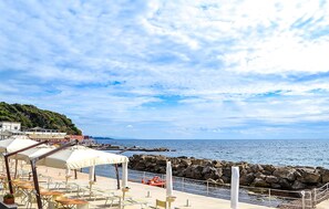 Une terrasse en bord de mer avec des places assises extérieures et une vue sur la mer.