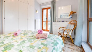 Un dormitorio con cama, cómoda, silla y ventana.