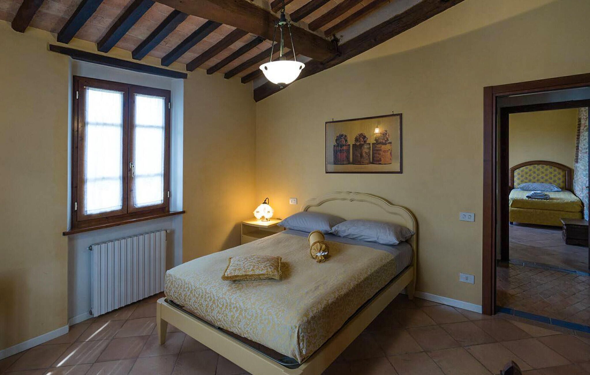 Ein Schlafzimmer mit Bett, Nachttisch, Fenster, Heizkörper und einem Bild an der Wand.