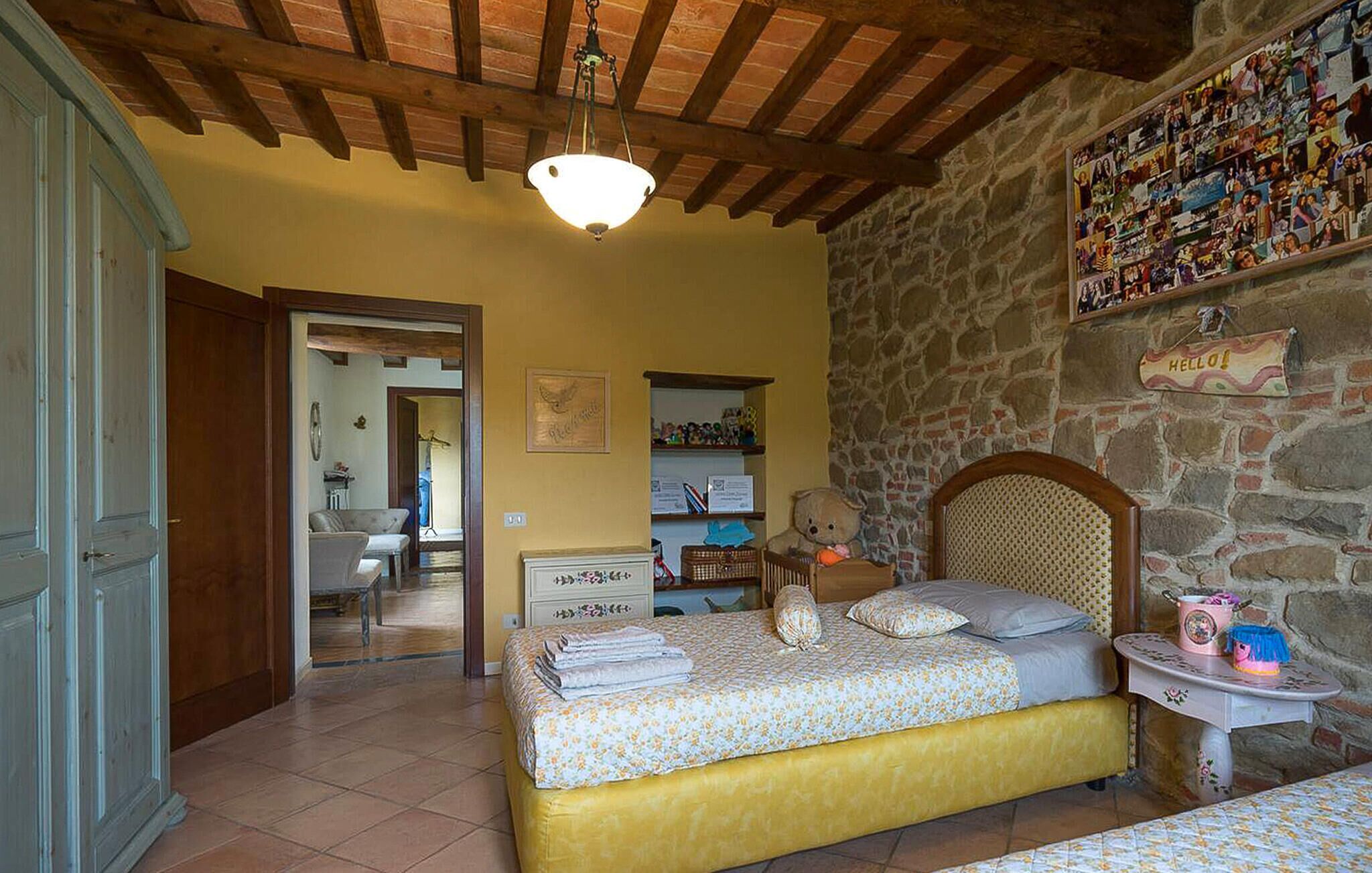 Une chambre à coucher avec un lit, une table de chevet, un ours en peluche et un mur orné d’une pancarte sur laquelle on peut lire « BONJOUR ! ».