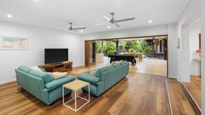 Ein geräumiges Wohnzimmer mit Türkis-Farbenen Sofas, einem Couchtisch, einem Flachbildfernseher und einem Billardtisch.