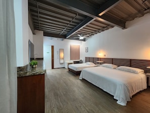 A hotel room with two beds, a wooden headboard, a small bedside table, a mirror, a potted plant, and a bathroom with a sink and mirror. - Torre Yaxche Urban Center (Cancun)
