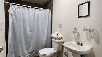 Un baño con cortina de ducha, inodoro, lavabo y una toalla en el suelo.