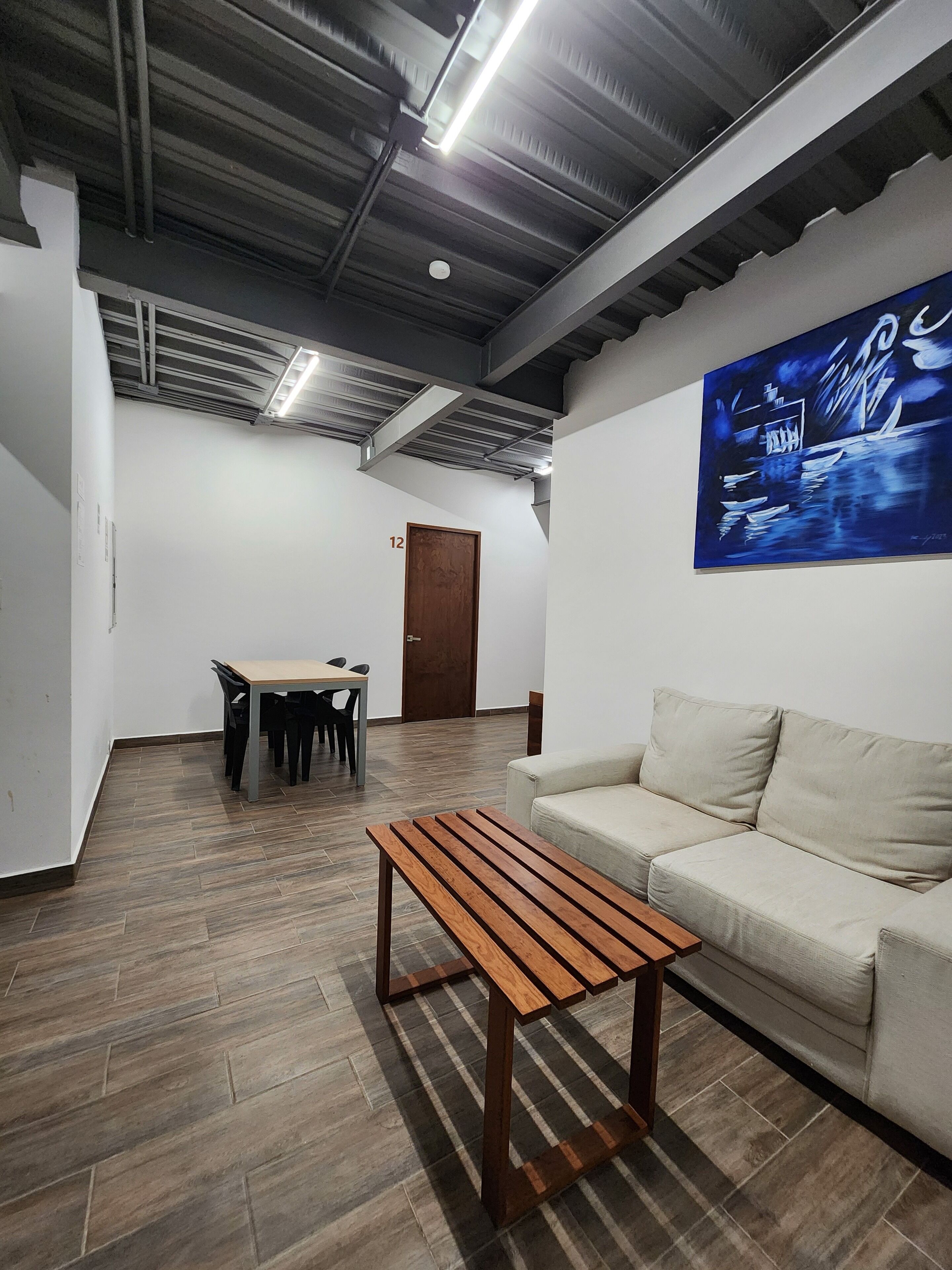 A modern interior with a wooden table, a sofa, and a painting on the wall.