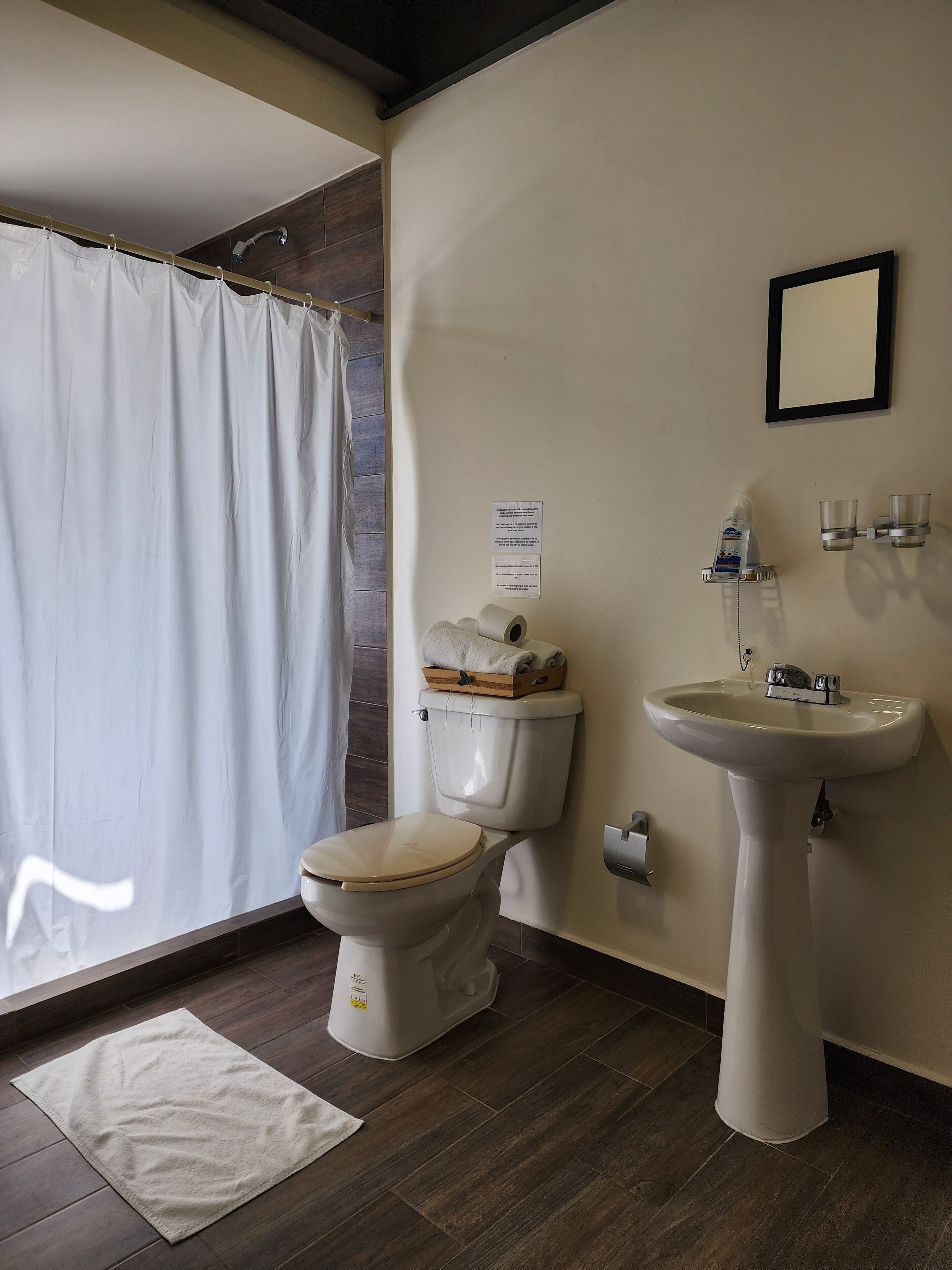Baño con inodoro, lavamanos y cortina de ducha.