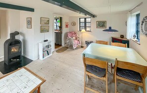 Een gezellige eethoek met een open haard, houten stoelen, een tafel en een boekenplank.