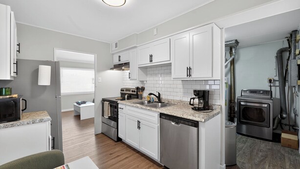 A modern kitchen with white cabinets, stainless steel appliances, and a wooden floor. - Central STL - Near Zoo, WashU, Quiet w/ Easy Parking! (St. Louis)
