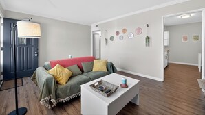 A living room with a sofa, a coffee table, a lamp, and a door. - Central STL - Near Zoo, WashU, Quiet w/ Easy Parking! (St. Louis)