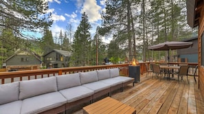 A deck with a sofa, table, chairs, and a fire pit.