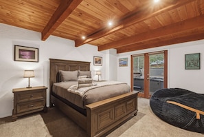 A bedroom with a wooden bed, nightstands, a bench, and a view through a glass door. - Palisades! Spacious Living, Views & Family Fun (Tahoe City)
