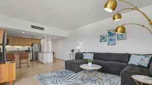 Una sala moderna con un sofá modular gris oscuro, una mesa de centro redonda y una alfombra azul estampada.