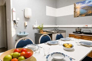 A dining area with a table set for four, a sink, a stove, and a painting on the wall. - Sefranda Near St.Julian's Ensuite Room 5, San Gwann, Malta (San Gwann)