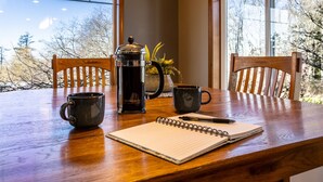 Ein Holztisch mit einer Kaffeemaschine, zwei Tassen und einem Notizbuch.