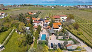 Luftaufnahme eines Wohngebiets mit Häusern, einem Schwimmbad und Weinbergen.