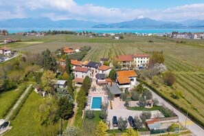 An aerial view of a residential area with houses, a swimming pool, and vineyards. - Residenza Lugana Pool & Garden in Peschiera Apt 4, Peschiera del Garda, Italy (Peschiera del Garda)