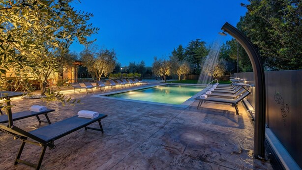 Ein Poolbereich mit Liegestühlen, einem Wasserspiel und einer Pergola.