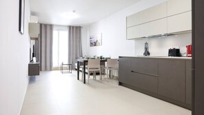 A modern kitchen with a dining area, featuring a large island, cabinets, and a view of the cityscape. - Central Sliema Stay Sea View -steps to Promenade (Sliema)