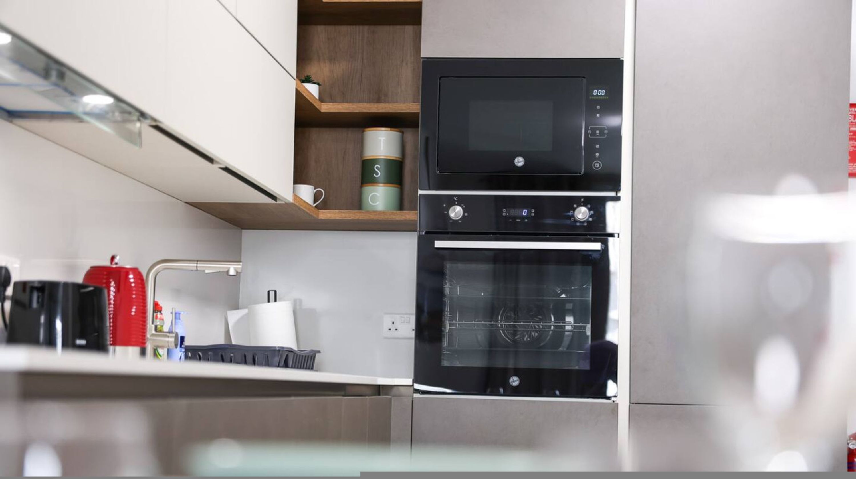 A modern kitchen with a built-in oven, microwave, and a coffee machine.