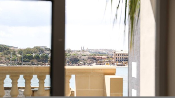 A balcony with a view of a coastal cityscape, including buildings and a body of water. - Central Sliema Stay Sea View -steps to Promenade (Sliema)