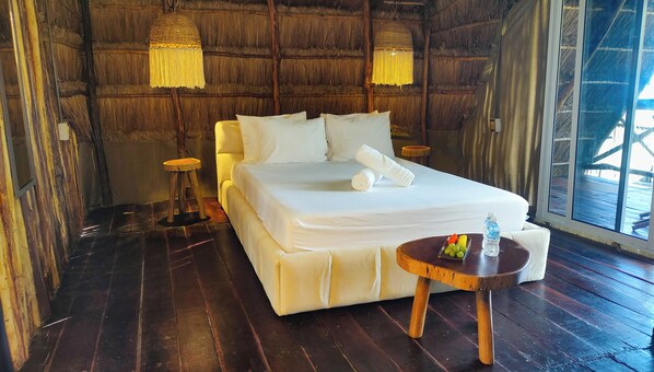 A room with a bed, bedside tables, a small round table with fruits and a bottle, and a large window. - Hotel Boutique Sylvie (Mahahual)