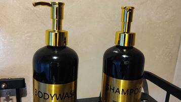 Deux bouteilles de gel douche et de shampoing sur une étagère en métal noir.