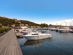 Ein Yachthafen mit vertäuten Booten, einer Holzpromenade und Gebäuden im Hintergrund.