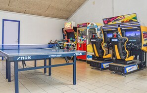 A ping pong table, arcade games, and a door in a room.
