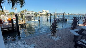 Un port de plaisance avec des bateaux amarrés, un ciel bleu dégagé et une promenade pavée agrémentée d’espaces pour s’asseoir.