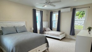 A bedroom with a large bed, a smaller bed, a desk, and a ceiling fan. - Stylish City Apt, Walk Everywhere (Pembroke Parish)