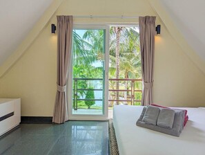 A bedroom with a bed, a nightstand, and a view of palm trees through a sliding glass door. - Villa with Private Pool (Ko Chang)