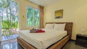 Une chambre avec un grand lit, une vue sur la verdure grâce à une porte coulissante, et un tableau accroché au mur.