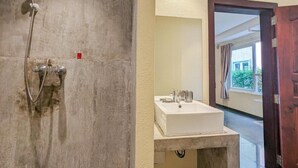 Une salle de bain avec douche, lavabo et vue sur l’extérieur.