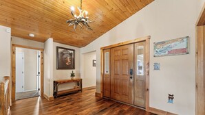Ein Holzboden-Flur mit einem Chandelier, einer Holztür und einem gerahmten Bild an der Wand.