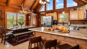 Een interieur van een chalet met een keuken, eethoek en een bar.