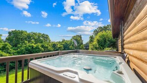 Een hottub op een houten terras, met uitzicht op bomen en een heldere lucht.