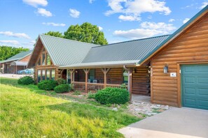 Eine Blockhütte mit Veranda, Garage und einem gepflegten Rasen.