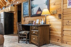 A cabin interior with a wooden desk, a chair, a lamp, and a framed picture of a canoe on water. - Thunder Ridge + Table Rock • Hot Tub • Fenced Yard • Pet Friendly (Ridgedale)