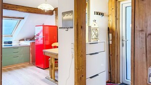 Cocina compacta con un refrigerador rojo, techo de madera y un pequeño comedor.
