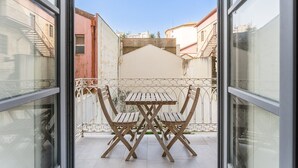 Un balcon avec une table et des chaises, une vue sur les bâtiments voisins et un ciel dégagé.