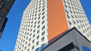 A multi-story hotel with a prominent orange section on the facade, multiple balconies, and a clear blue sky in the background. - 용두산공원 뷰 및 바다뷰, 지하철역 2분거리!! 숙소 바로 앞 먹자골목, 국제시장 6분거리!! (Busan)