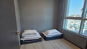 A room with two beds, a large window with a city view, and a ceiling light fixture. - 용두산공원 뷰 및 바다뷰, 지하철역 2분거리!! 숙소 바로 앞 먹자골목, 국제시장 6분거리!! (Busan)
