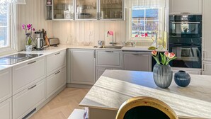 A modern kitchen with white cabinetry, a marble countertop, and a built-in oven.