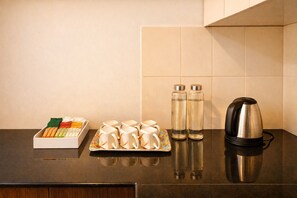 Una encimera de cocina con un juego de té, dos botellas de agua y una tetera.