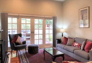 A living room with a sofa, armchair, ottoman, and a glass coffee table.